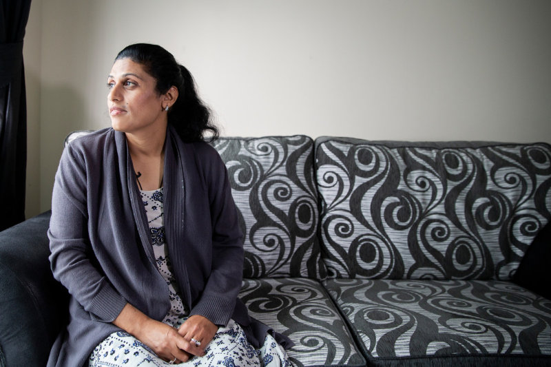 A woman sitting on a couch, looking out the window.