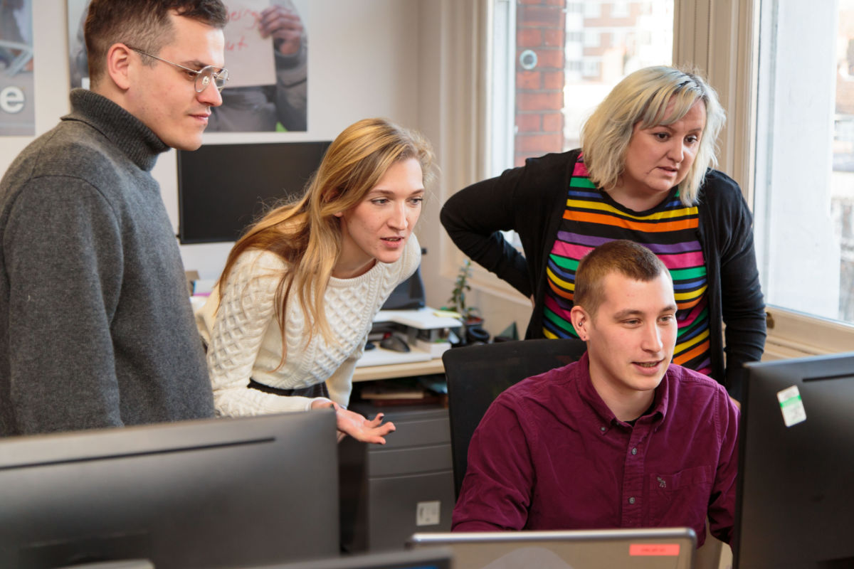 Four people in a Shelter office looking at a computer screen.