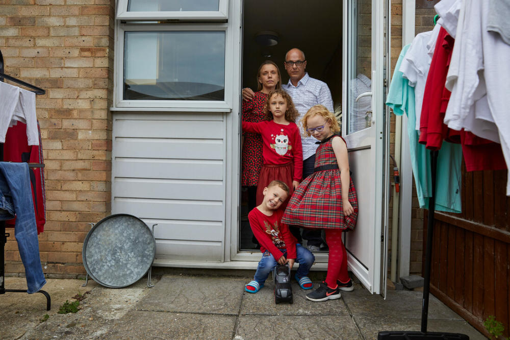 A man, his wife, and their 3 children stand in the back doorway or their home.