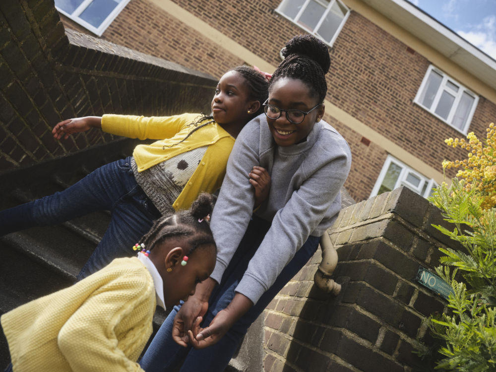 Woman and her two daughters outside their social housing home