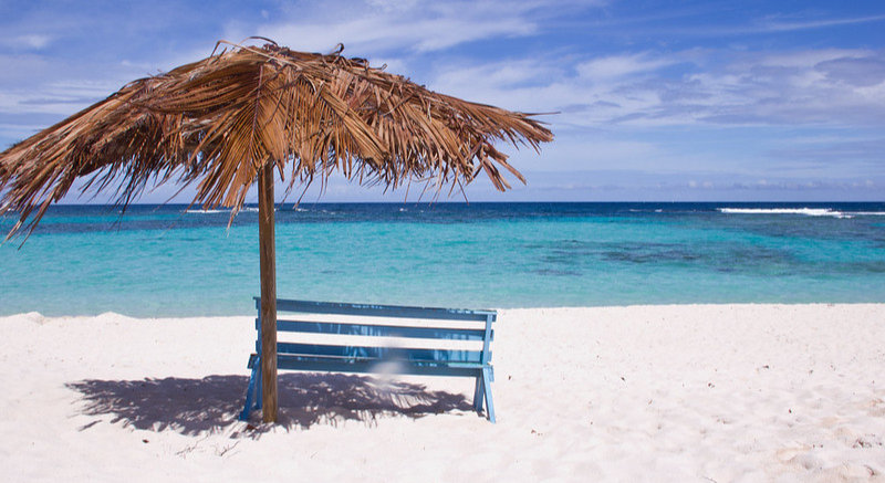 Bench on sandy beach overlooking the ocean